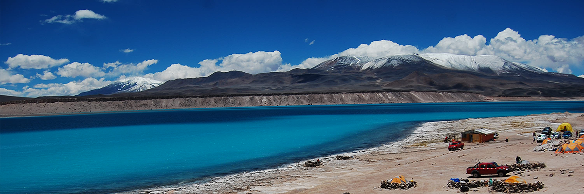 La Laguna Verde con sus aguas turquesas, con flamencos a la orilla y volcanes al fondo.