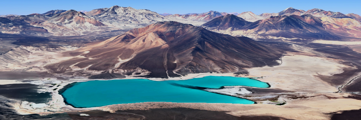 Paisaje panorámico del desierto de Atacama con varios volcanes nevados en el horizonte bajo un cielo azul intenso.