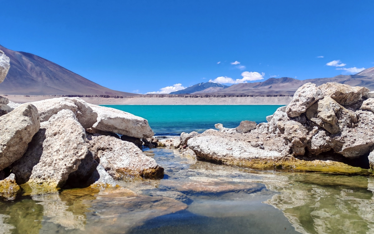 Natural hot springs pool overlooking the turquoise Laguna Verde during the Ojos del Salado 14-day expedition.