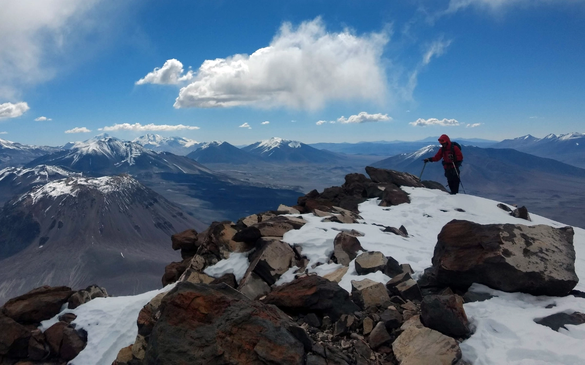Mountaineer standing on the summit ridge of Nevado San Francisco at 6,018 m during the Ojos del Salado 14-day expedition.