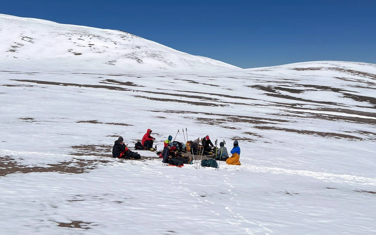 Mountaineers taking a rest break on the snow slope of Ojos del Salado before reaching the summit.